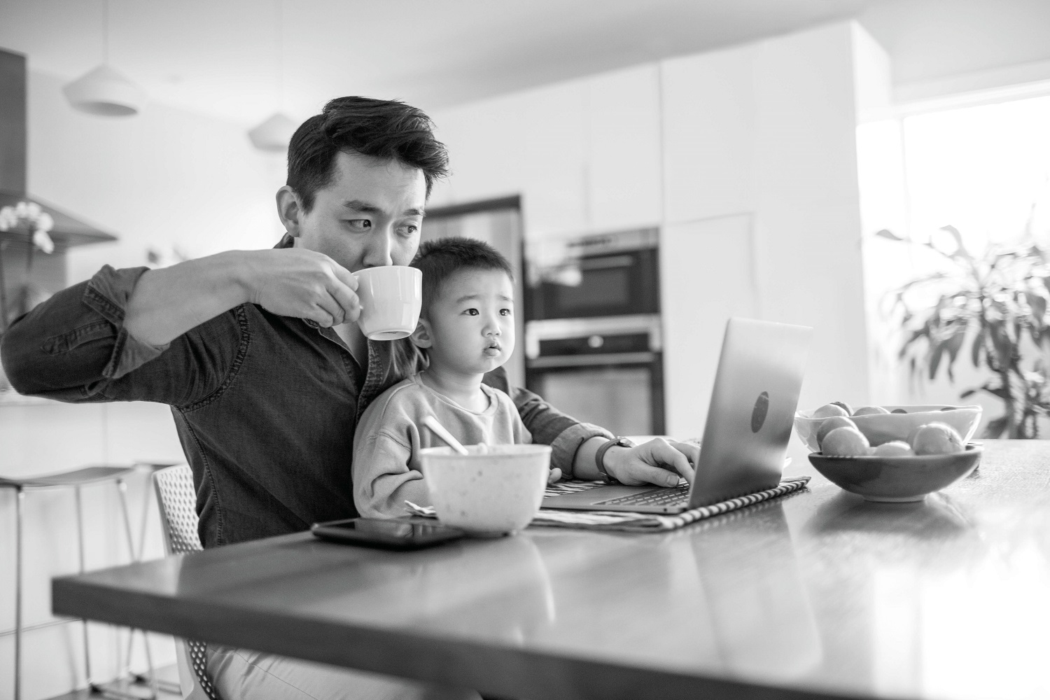 Dad on laptop with son on his lap 