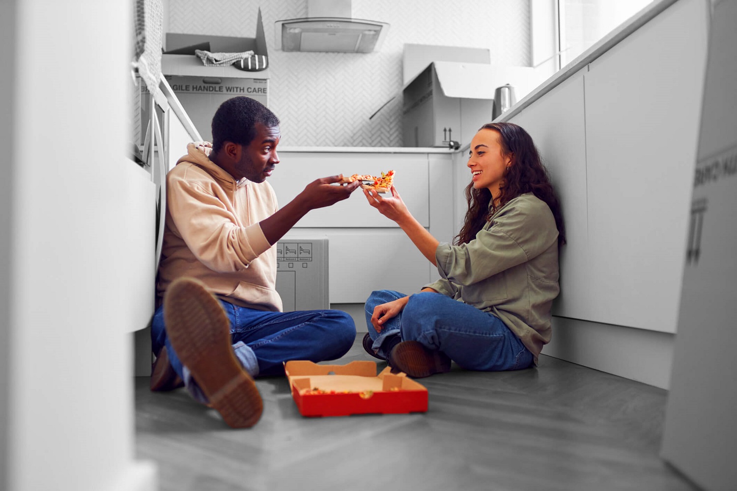 First time buyers eating pizza on floor 